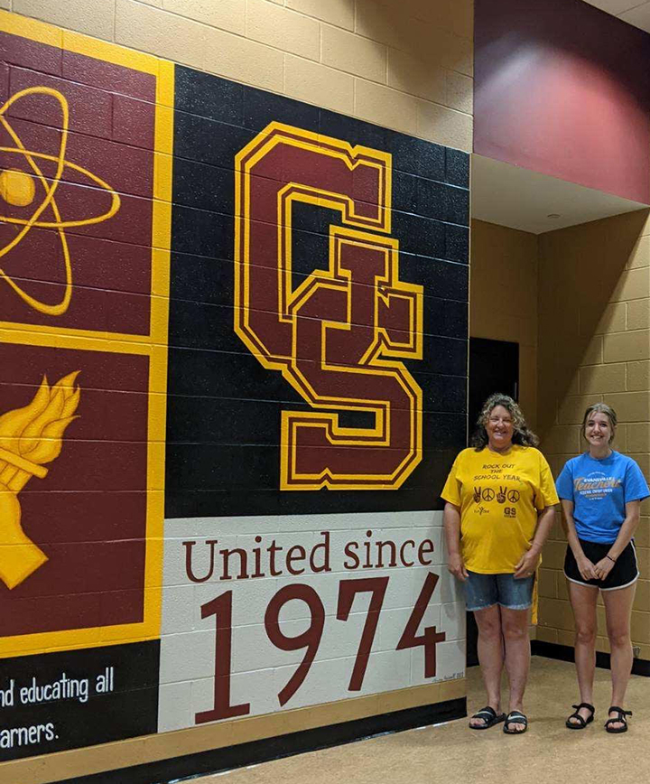 Art teacher Laura Russell and Geneva Sagers stand by their freshly completed mural.