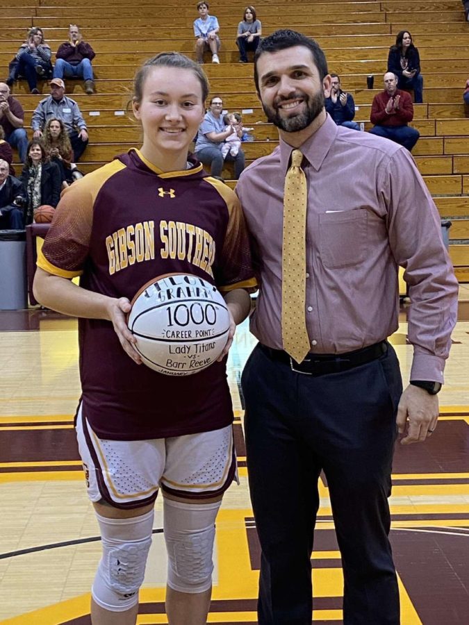 Coach Kyle Brasher presents junior Chloey Graham with her commemorative 1000th point basketball.