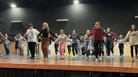 The cast of Big Fish works on choreography for a large group number.
