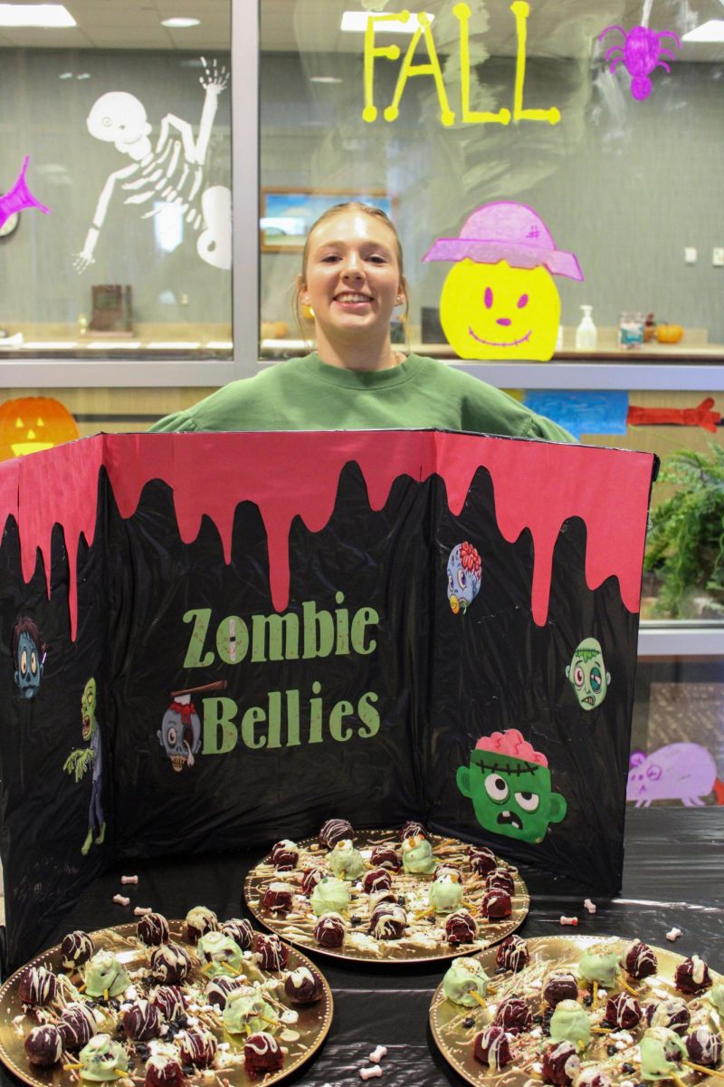 Shaleigh Martin poses in front of her teams zombie poster.