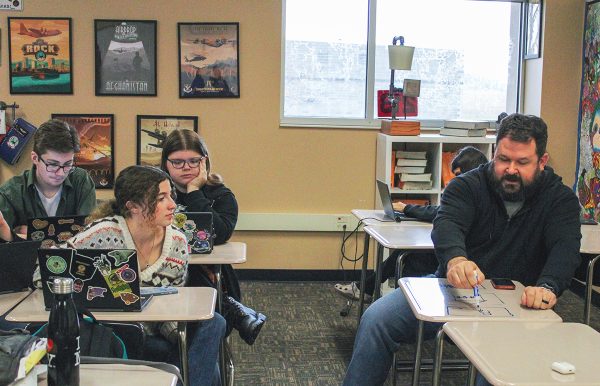 Film Literature teacher Ian Gamroth helps senior Madison Render work through her horror story, creating a temporary storyboard on a classroom desk.