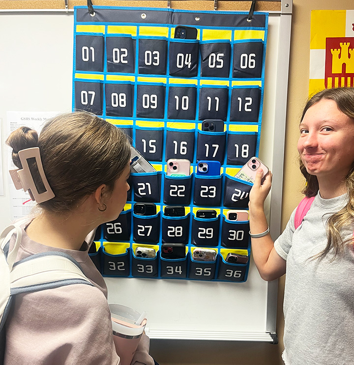 Juniors Abigail Swader and Kynlee Reeves put their phones in a numbered slot in Claudia Kinnaird's seventh period Spanish 3 class. Many teachers use these cell phone holders in their classrooms.