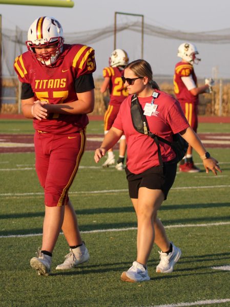 Athletic trainer Jenna Sparks listens to junior Gavin McEllhiney before examining his wrist on the sideline.